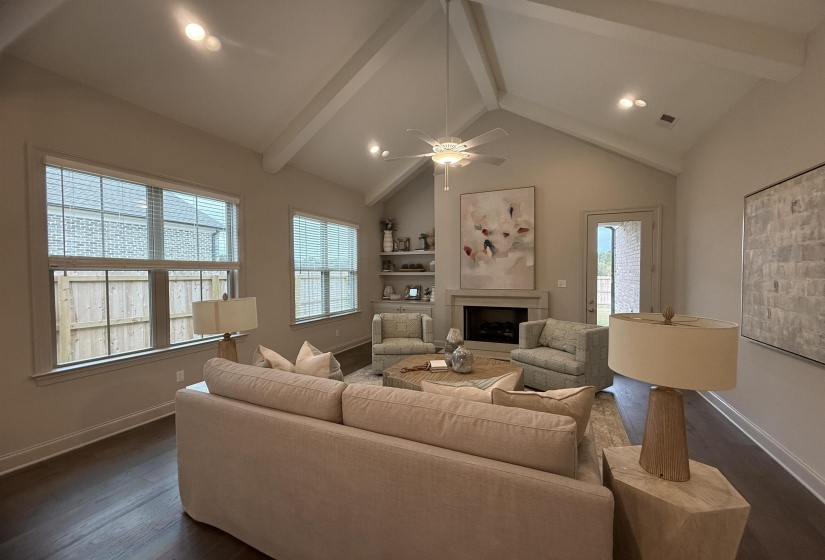 Living area featuring beam ceiling, a fireplace, dark wood-type flooring, recessed lighting, and high vaulted ceiling