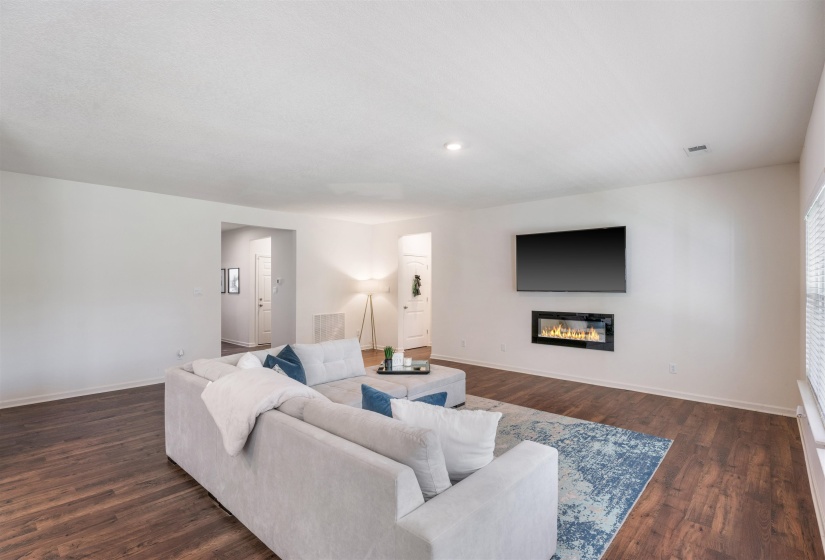 Living area featuring dark wood-style floors, baseboards, a glass covered fireplace, and recessed lighting