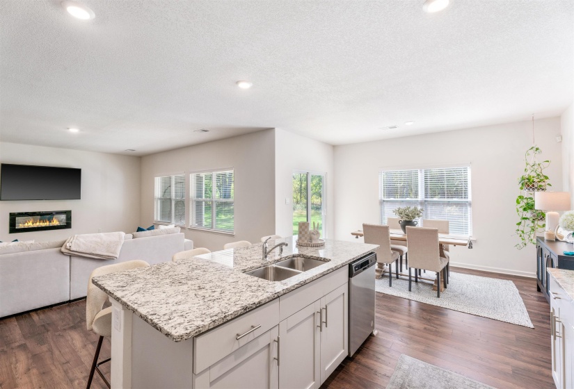 Kitchen with a sink, dishwasher, a center island with sink, plenty of natural light, and a textured ceiling