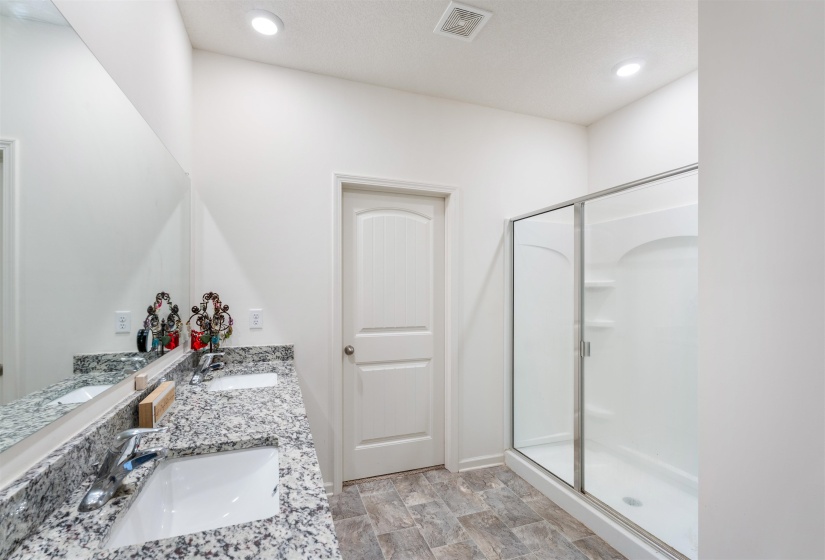 Bathroom featuring a shower stall, double vanity, and recessed lighting