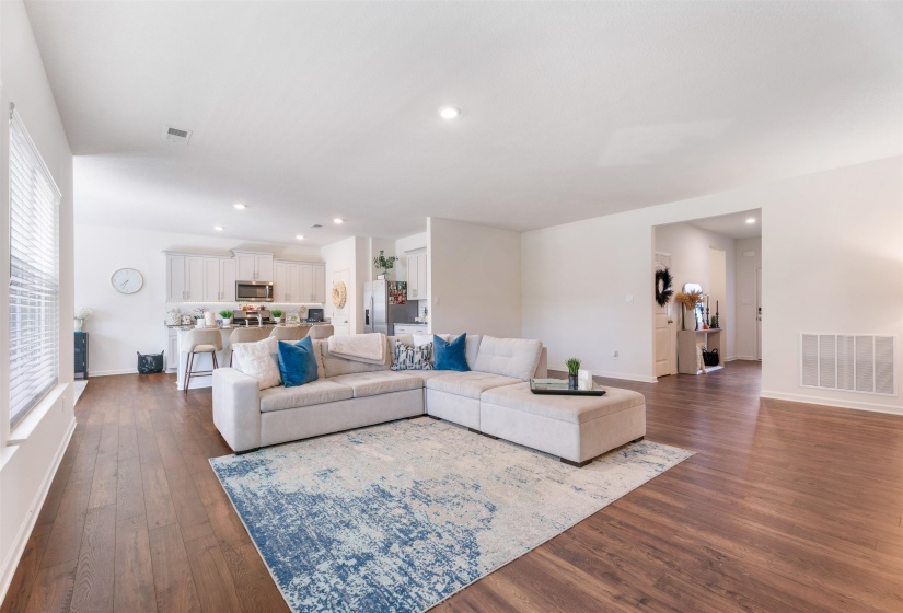 Living room featuring dark wood-type flooring, healthy amount of natural light, baseboards, and recessed lighting