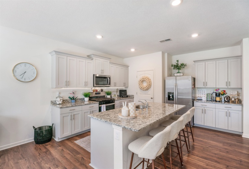 Kitchen featuring appliances with stainless steel finishes, a sink, dark wood-style floors, a kitchen bar, and recessed lighting