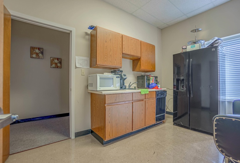 Kitchen with black refrigerator with ice dispenser and a paneled ceiling