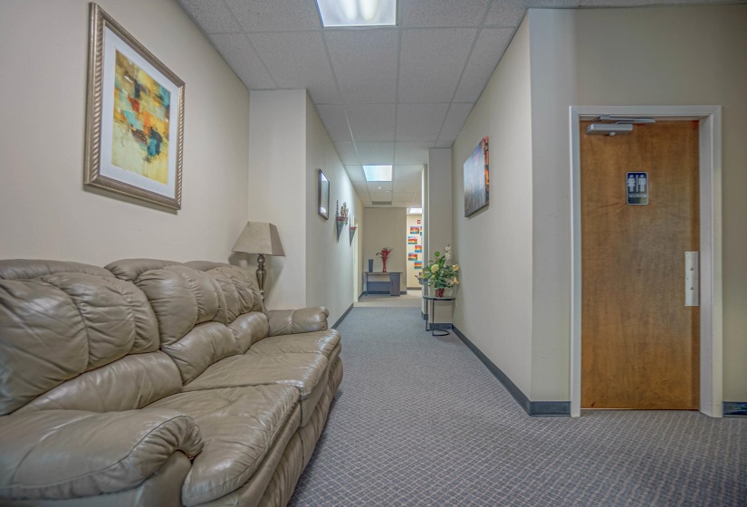 Hall with a paneled ceiling and light colored carpet