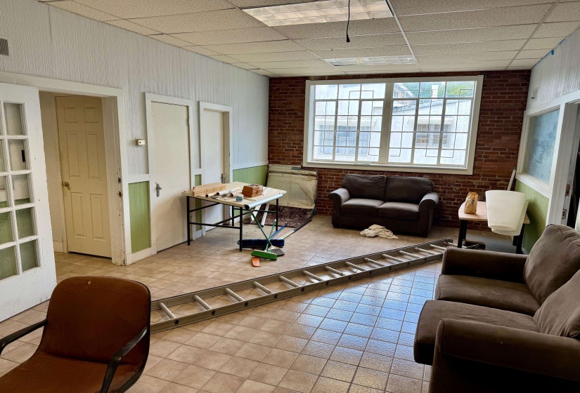 Tiled living area with a drop ceiling and brick wall