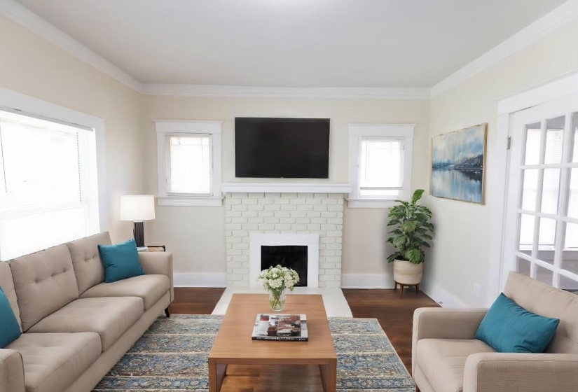 Living room featuring a brick fireplace, ornamental molding, and dark hardwood / wood-style flooring