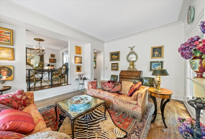 Living area with ornamental molding, wood finished floors, and a chandelier