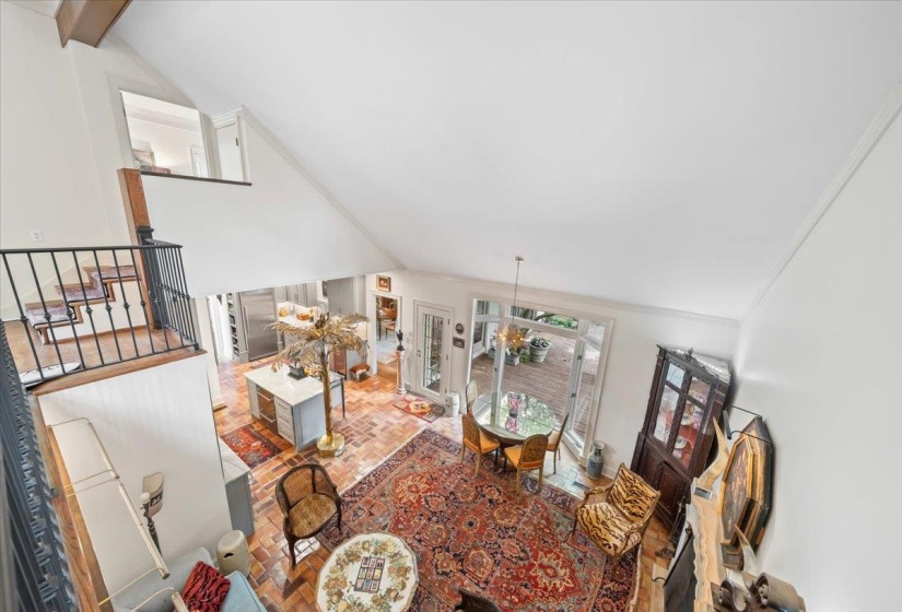 Living room featuring vaulted ceiling, stairs, brick patterned floors, and ornamental molding
