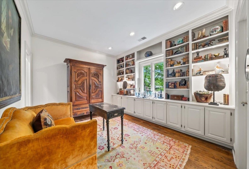 Sitting room or extra bedroom has built in shelving and a closet for organizing. Featuring crown molding, light wood-style flooring, and recessed lighting