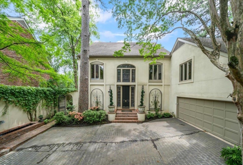 View of front facade with stucco siding, decorative driveway, and a garage