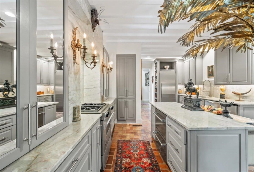 Kitchen with gray cabinetry, premium appliances, backsplash, a center island, and brick floors