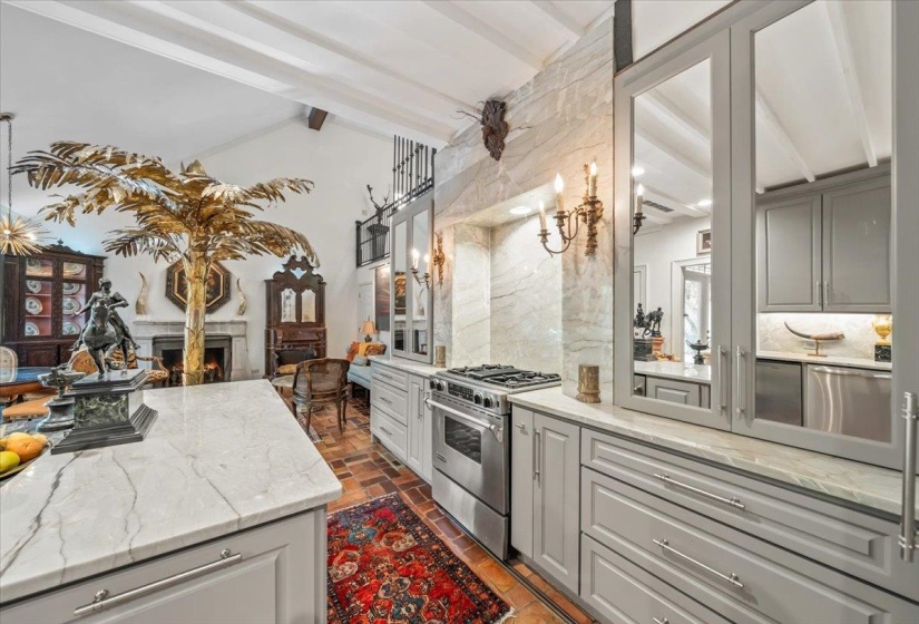 Kitchen with high end stainless steel range, decorative backsplash, a lit fireplace, light stone countertops, and gray cabinets