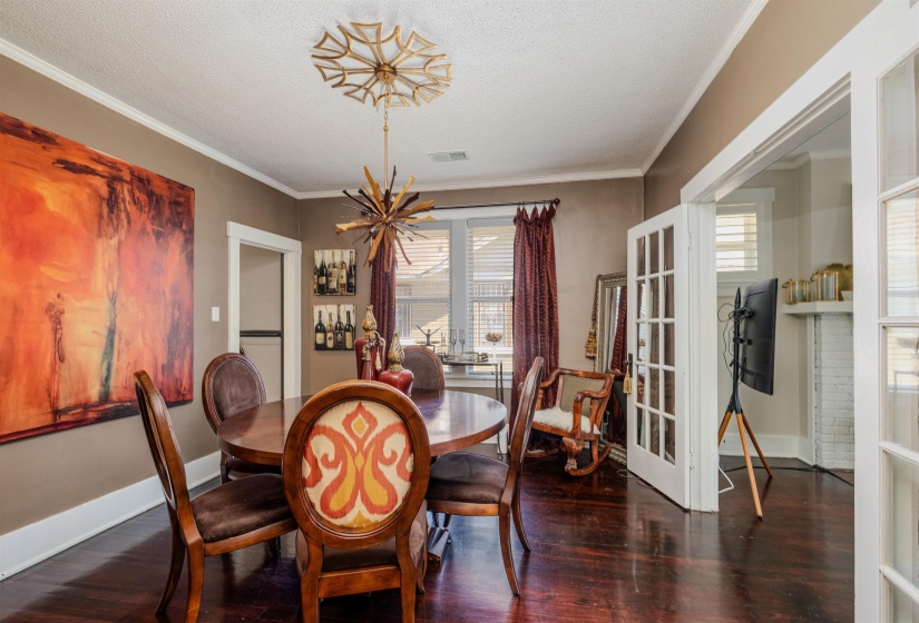 Dining space with french doors, healthy amount of natural light, wood finished floors, baseboards, and a textured ceiling