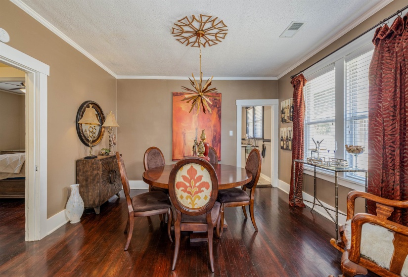 Dining room featuring wood finished floors, baseboards, crown molding, and a textured ceiling