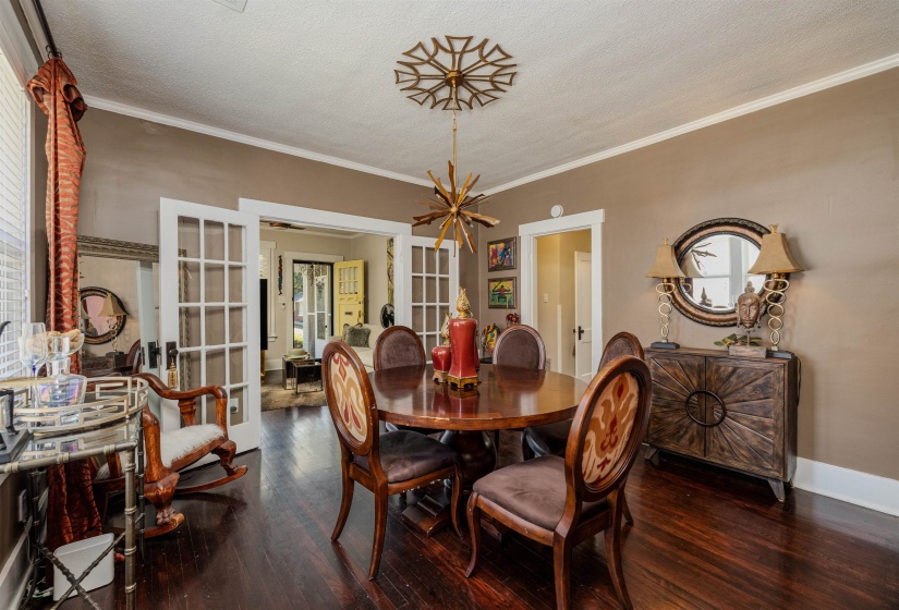 Dining space with french doors, wood finished floors, ornamental molding, a textured ceiling, and a chandelier