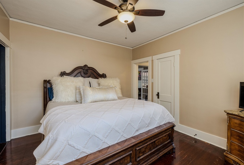 Bedroom featuring baseboards, crown molding, wood finished floors, and ceiling fan