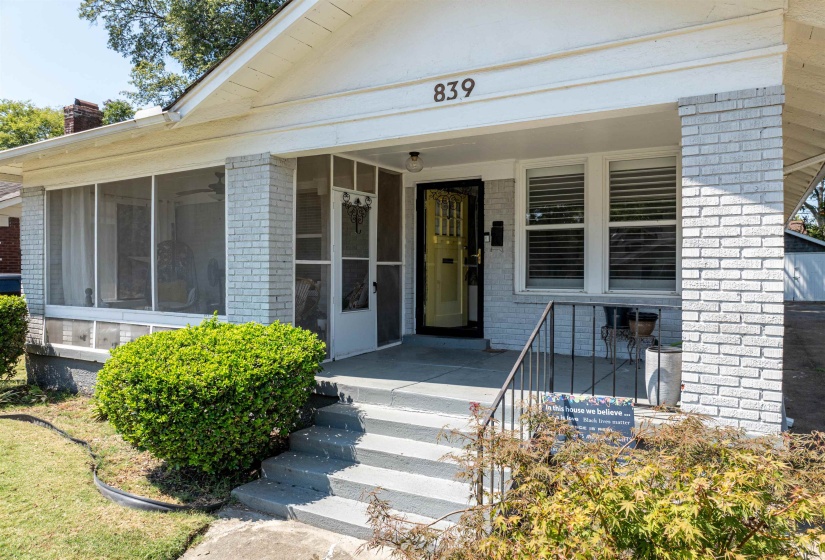 View of exterior entry featuring brick siding, covered porch, central air condition unit, and a chimney