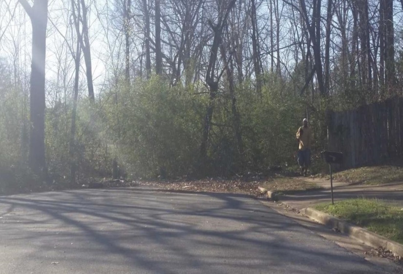 View of asphalt street featuring curbs and a view of trees