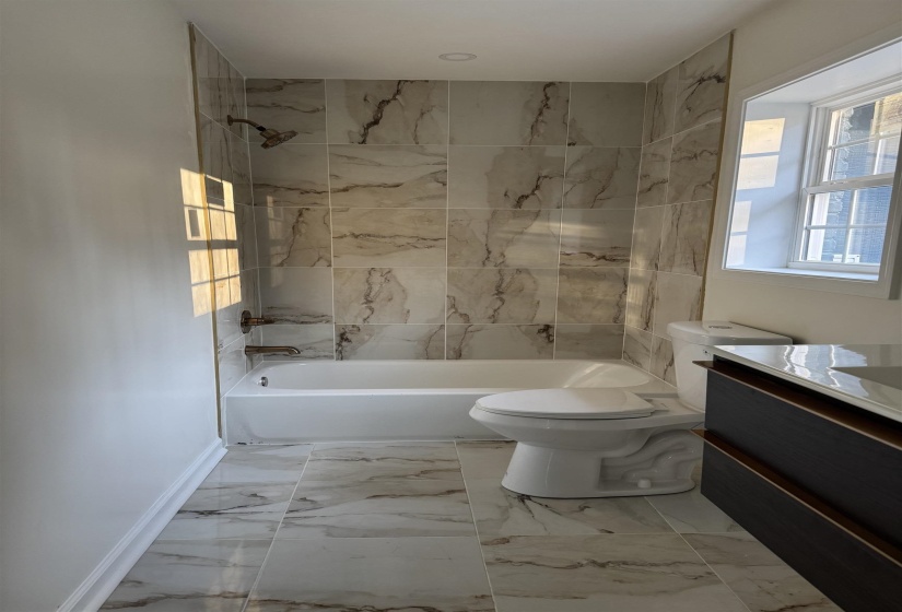Full bathroom with marble finish floor, toilet, vanity, and bathing tub / shower combination