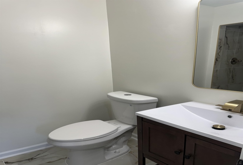 Bathroom with marble finish floor, vanity, toilet, and baseboards