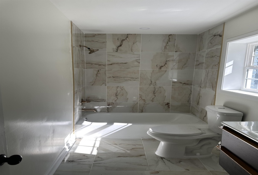 Bathroom featuring marble finish floor, toilet, vanity, and shower / bathtub combination