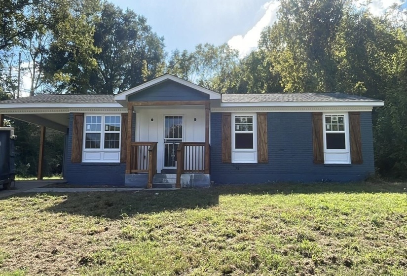 View of front of property with an attached carport, a front yard, and roof with shingles