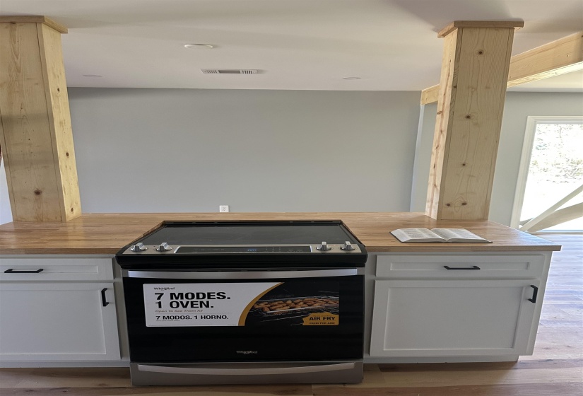 Kitchen featuring visible vents, light wood-style flooring, stainless steel electric range oven, wood counters, and white cabinetry