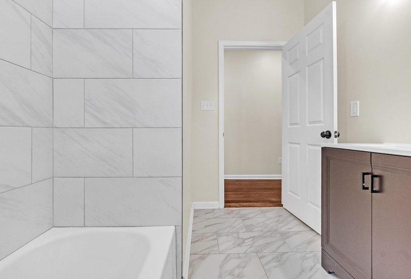 Full bathroom featuring marble finish flooring, a bath, and vanity