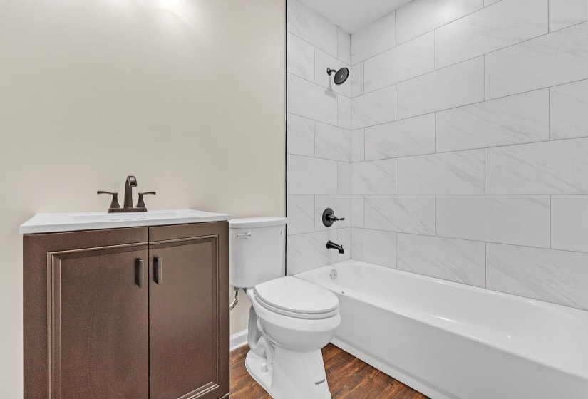 Bathroom featuring toilet, wood finished floors, vanity, and shower / bathtub combination