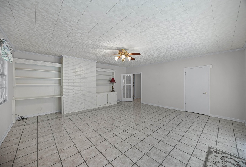 Unfurnished living room with a textured ceiling, built in shelves, light tile patterned floors, and ceiling fan