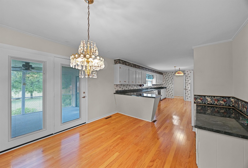 Kitchen with light hardwood / wood-style floors, an inviting chandelier, a healthy amount of sunlight, and kitchen peninsula