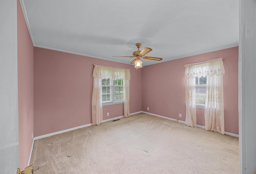 Empty room featuring ornamental molding, light colored carpet, and ceiling fan