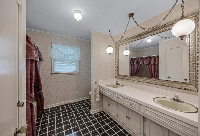 Bathroom featuring tile patterned flooring, ornamental molding, toilet, and dual bowl vanity