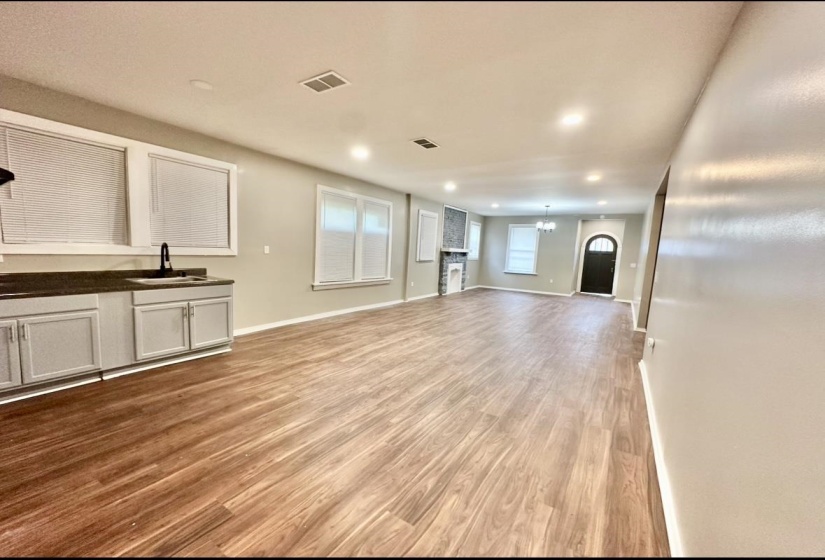 Unfurnished living room with a sink, a chandelier, light wood-style flooring, recessed lighting, and baseboards