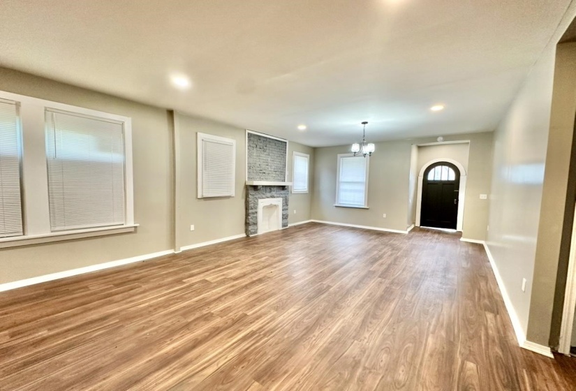 Unfurnished living room with wood finished floors, a chandelier, a fireplace, baseboards, and recessed lighting