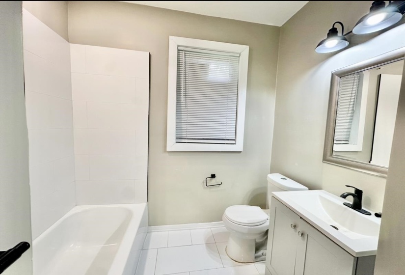 Bathroom featuring toilet, vanity, tile patterned floors, baseboards, and bathtub / shower combination