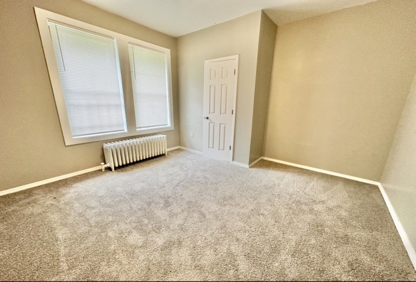 Carpeted spare room featuring radiator and baseboards