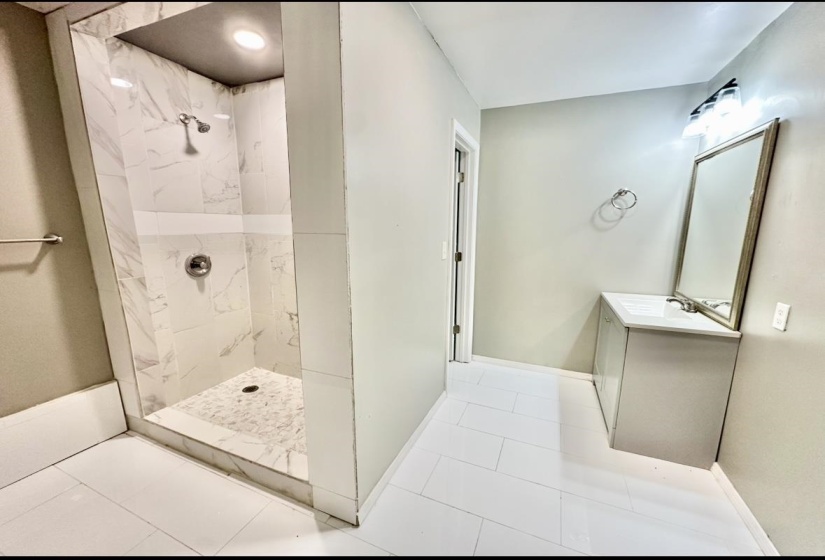 Full bathroom with tiled shower, vanity, tile patterned floors, and baseboards
