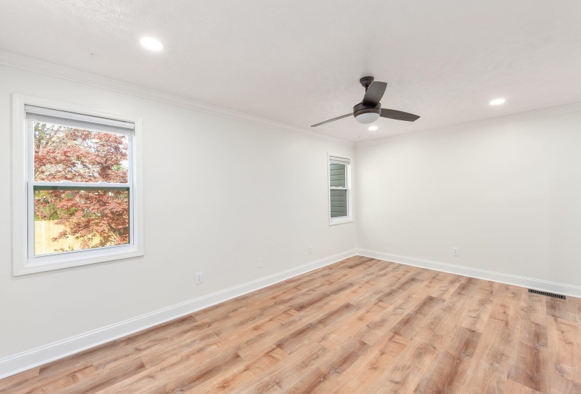 Spare room featuring baseboards, visible vents, light wood-style flooring, and ornamental molding