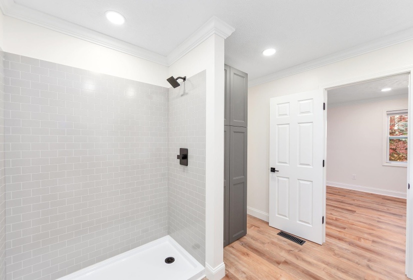 Bathroom with a shower stall, visible vents, and ornamental molding