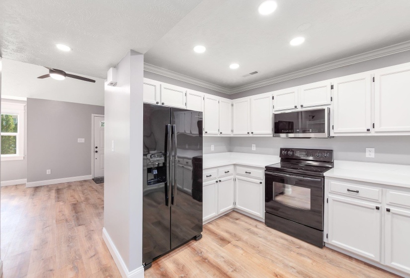Kitchen featuring light wood-style flooring, white cabinetry, and black appliances