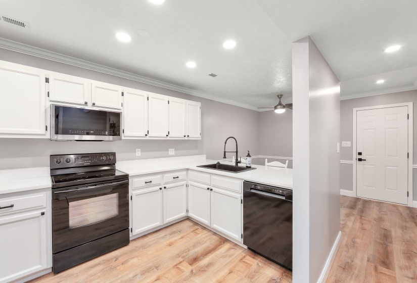 Kitchen featuring visible vents, light wood finished floors, ceiling fan, a sink, and black appliances