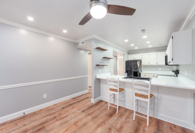 Kitchen with a peninsula, ceiling fan, a sink, light wood-style floors, and stove
