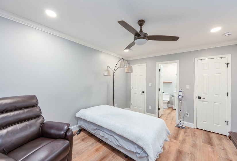 Bedroom with ensuite bathroom, crown molding, light wood finished floors, baseboards, and recessed lighting