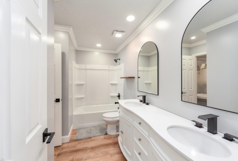 Bathroom featuring toilet, a sink, crown molding, and wood finished floors