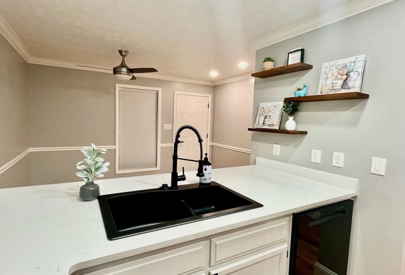 Kitchen with light countertops, dishwasher, ornamental molding, a sink, and open shelves