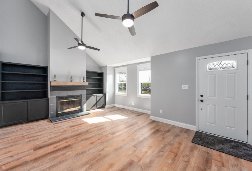 Foyer with a ceiling fan, high vaulted ceiling, baseboards, light wood-style flooring, and a fireplace