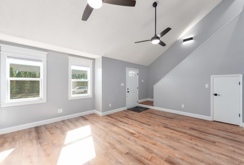 Entrance foyer featuring a ceiling fan, vaulted ceiling, baseboards, and light wood-style flooring