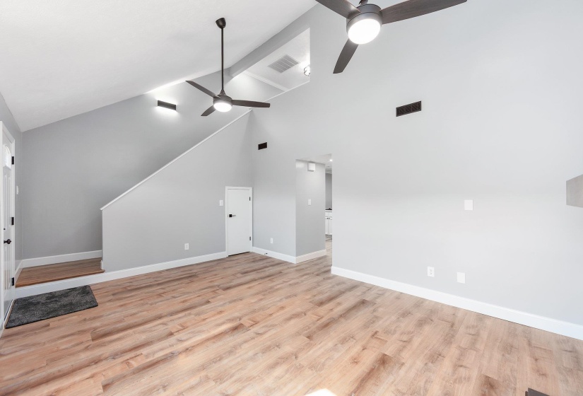 Unfurnished living room with light wood-type flooring, a ceiling fan, baseboards, and visible vents