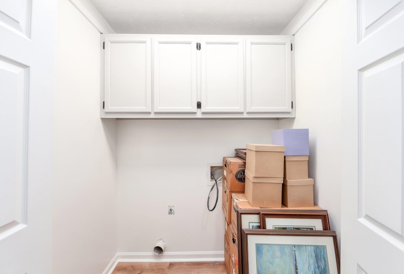 Laundry area with wood finished floors, hookup for an electric dryer, baseboards, cabinet space, and hookup for a washing machine